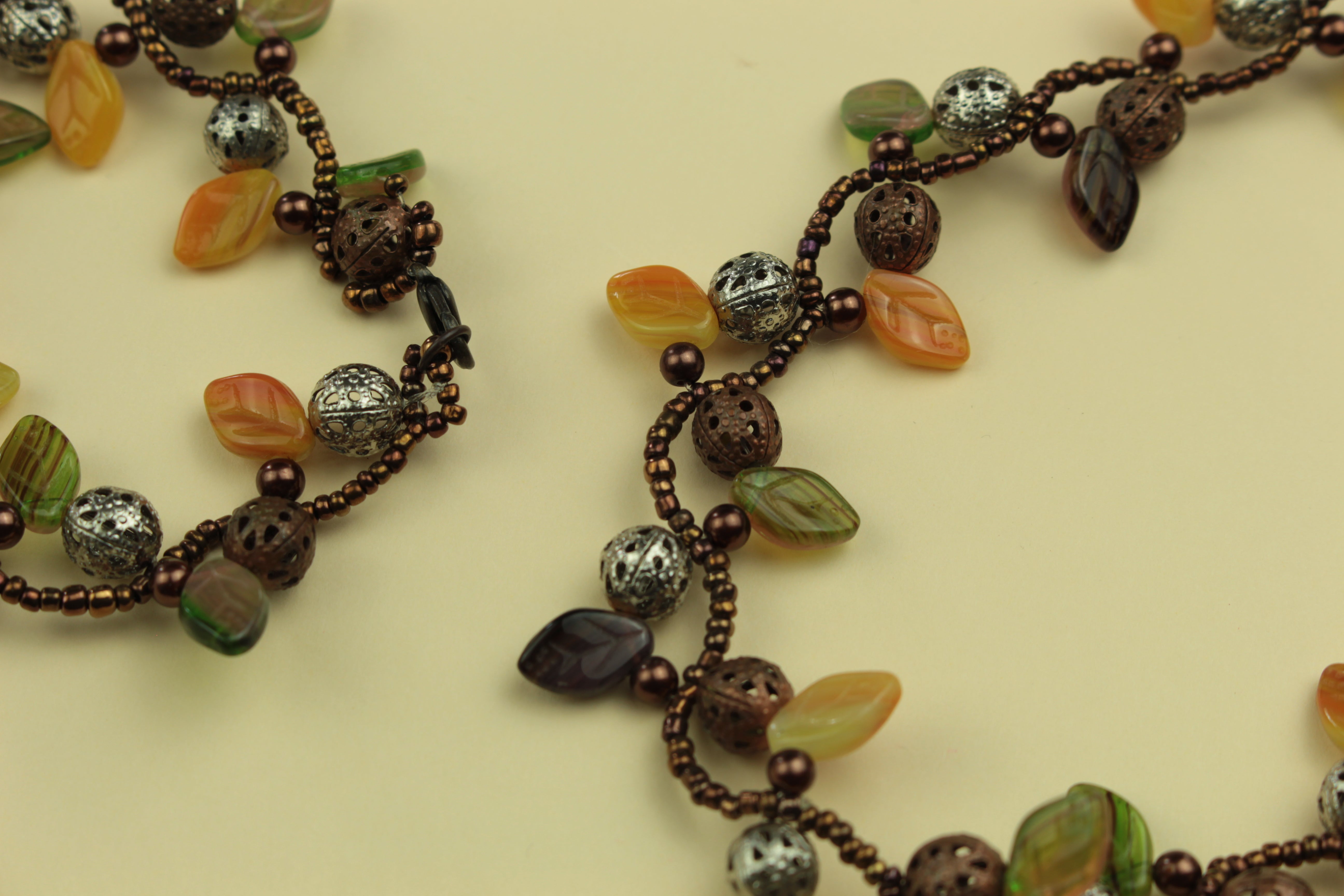 Autumn leaf and metal bead statement necklace on a warm cream background, handmade in Tauranga