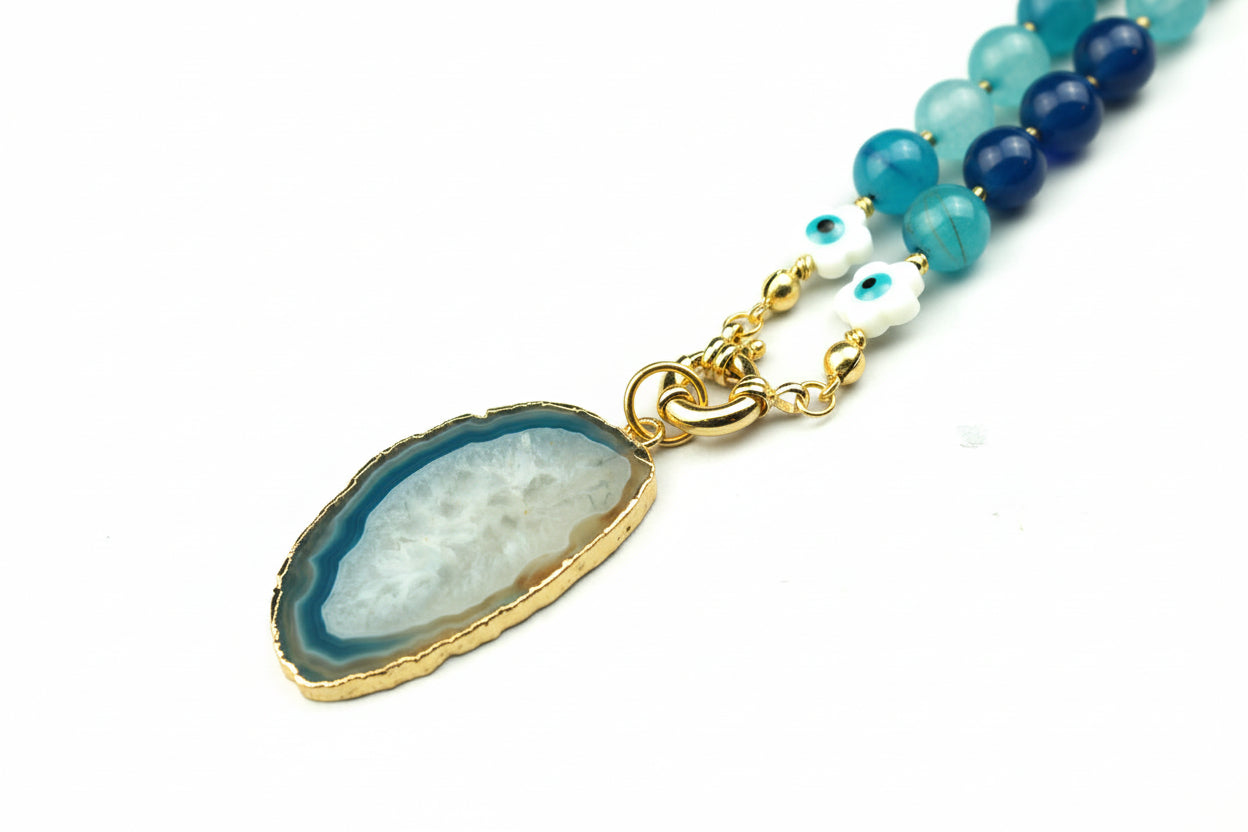 Blue agate beaded necklace with a natural geode pendant on a warm cream background, handmade in Tauranga