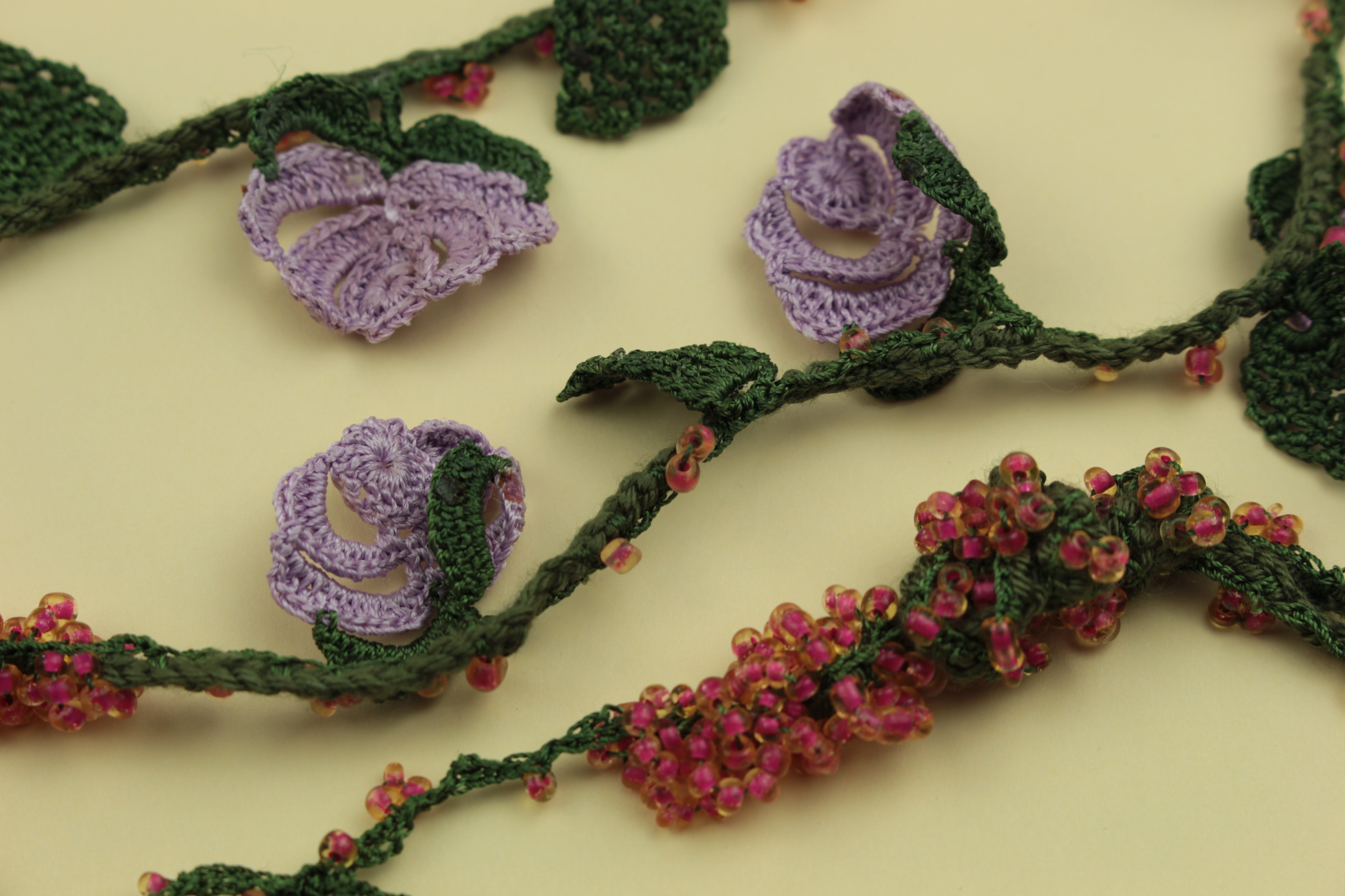 Crochet rose garland necklace on a warm cream background, handmade in Tauranga