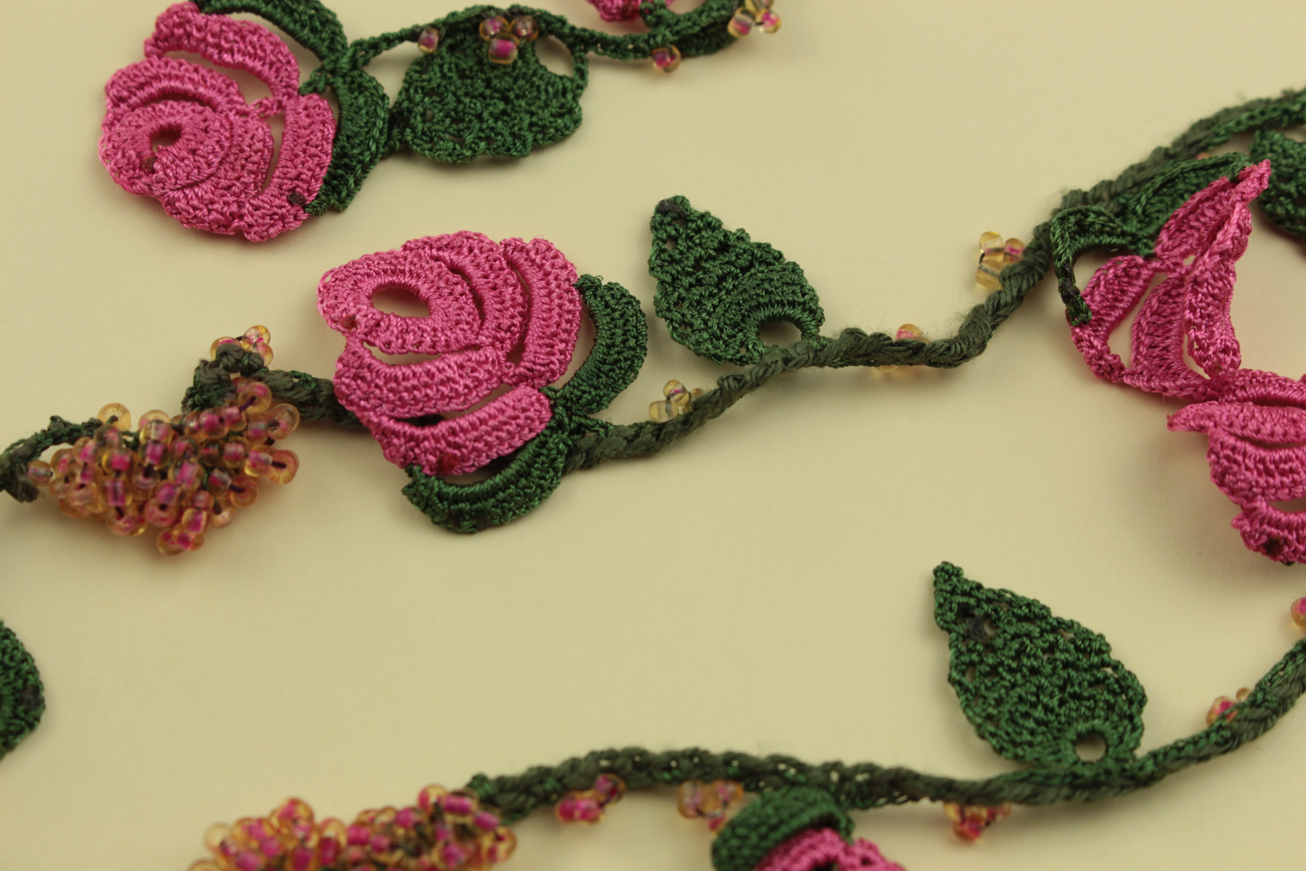 Crochet rose vine necklace on a warm cream background, handmade in Tauranga