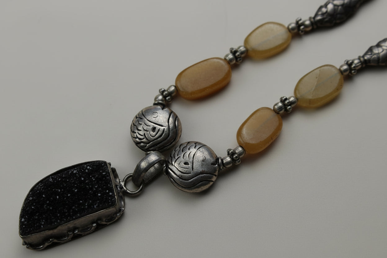 Real amber and silver fish pendant necklace on a warm cream background, handmade in Tauranga